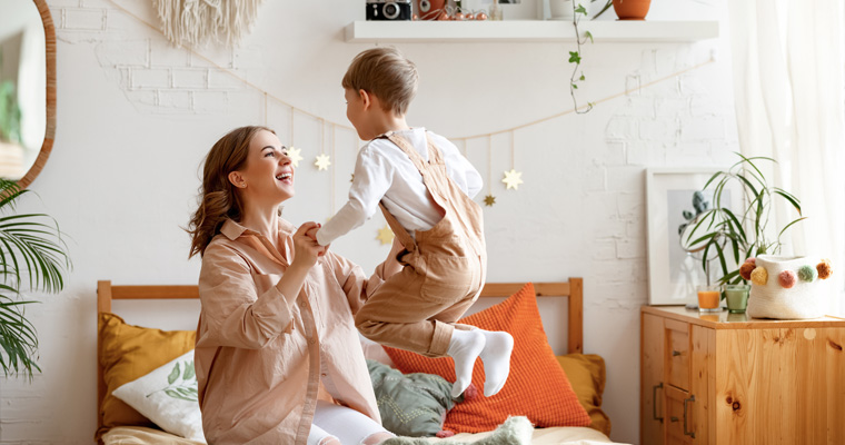 Happy woman and boy playing in bedroom