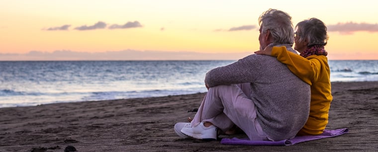 Senior couple sitting on a beach at sunset