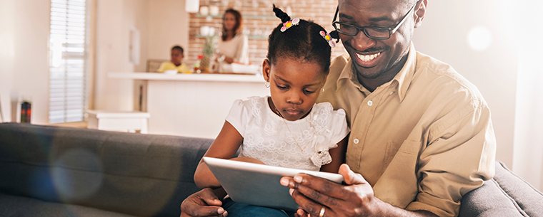 African American father and daughter g at an iPad