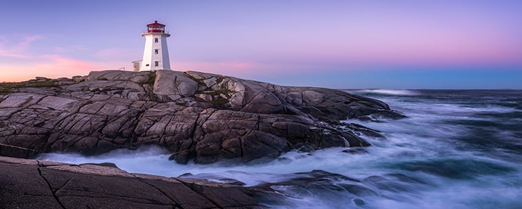 shoreline at sunset with lighthouse sitting on top of rocks