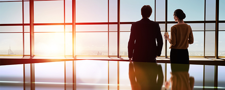 Business man and woman looking out the window of conference room