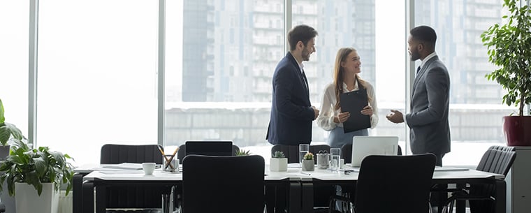 Three business people standing in a room talking